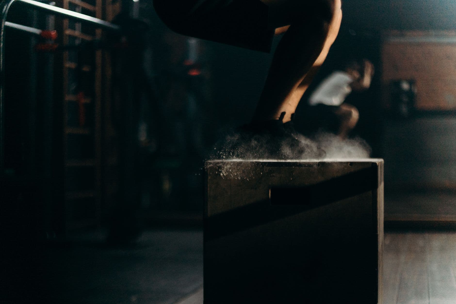A dynamic gym scene with a person performing box jumps, showcasing strength training indoors.
