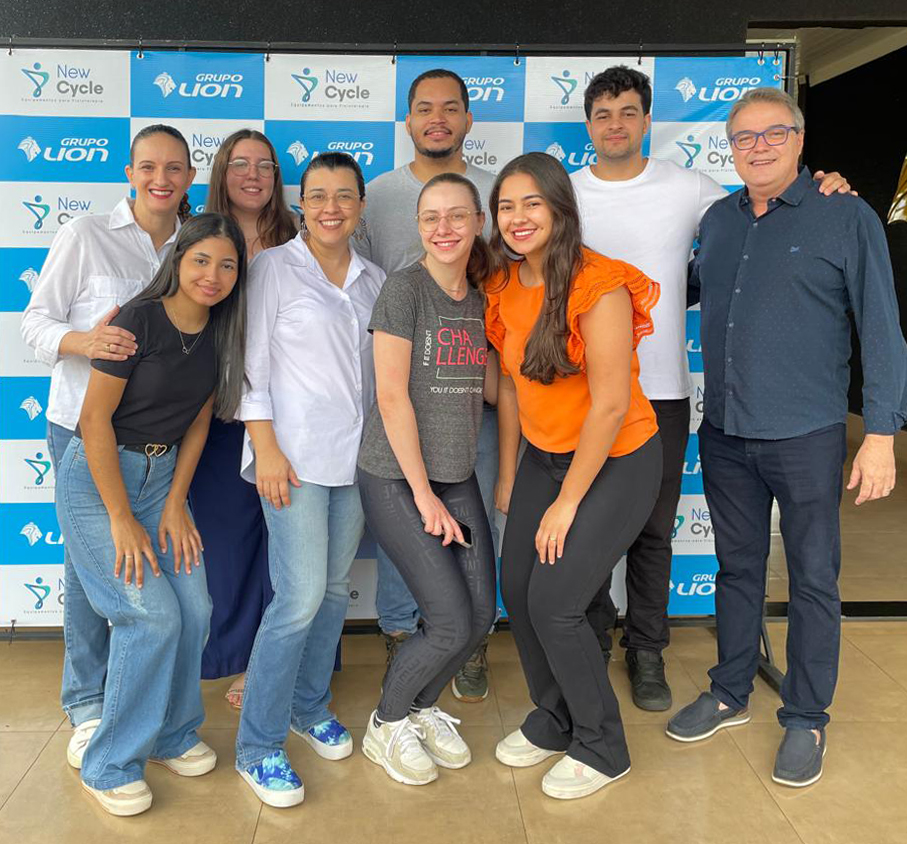 InterFisio: Conexão e Inovação: pessoas posando em frente a um painel com os logotipos das empresas, simbolizando parceria e colaboração.